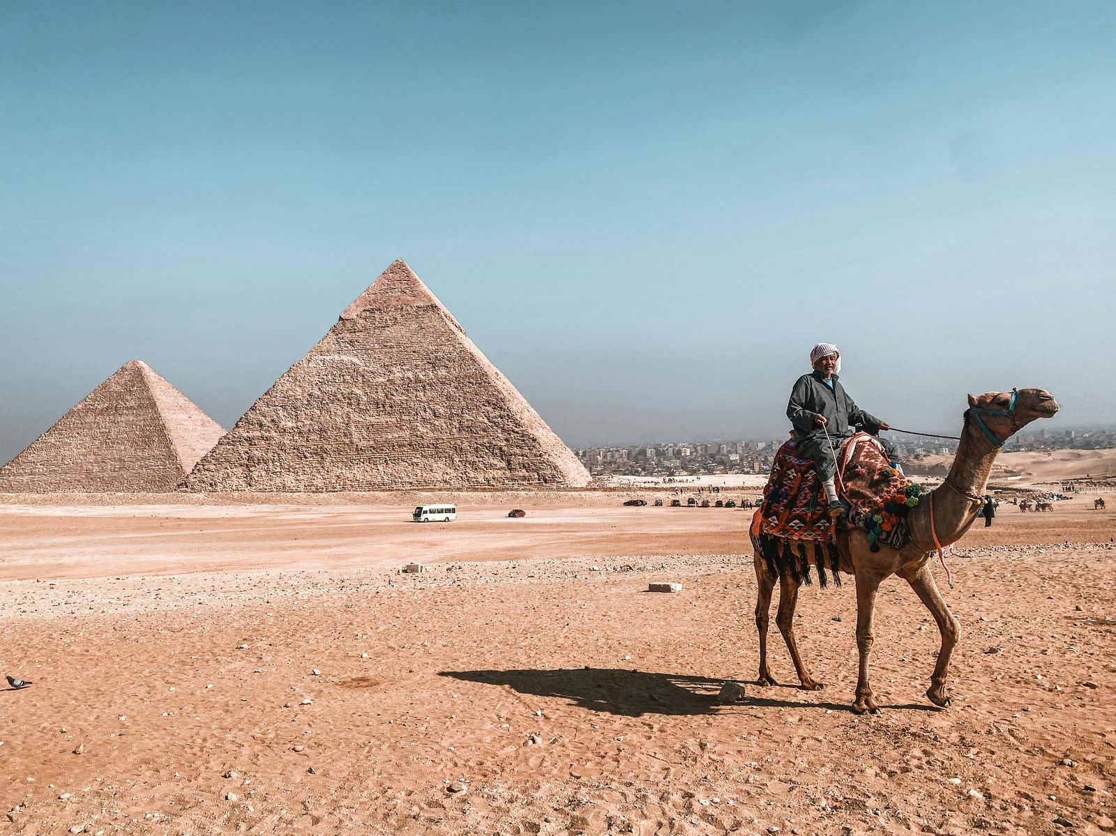 A camel rider passing the pyramids of Giza